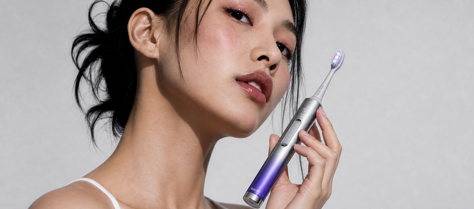 Woman holding a purple electric toothbrush beside her face
