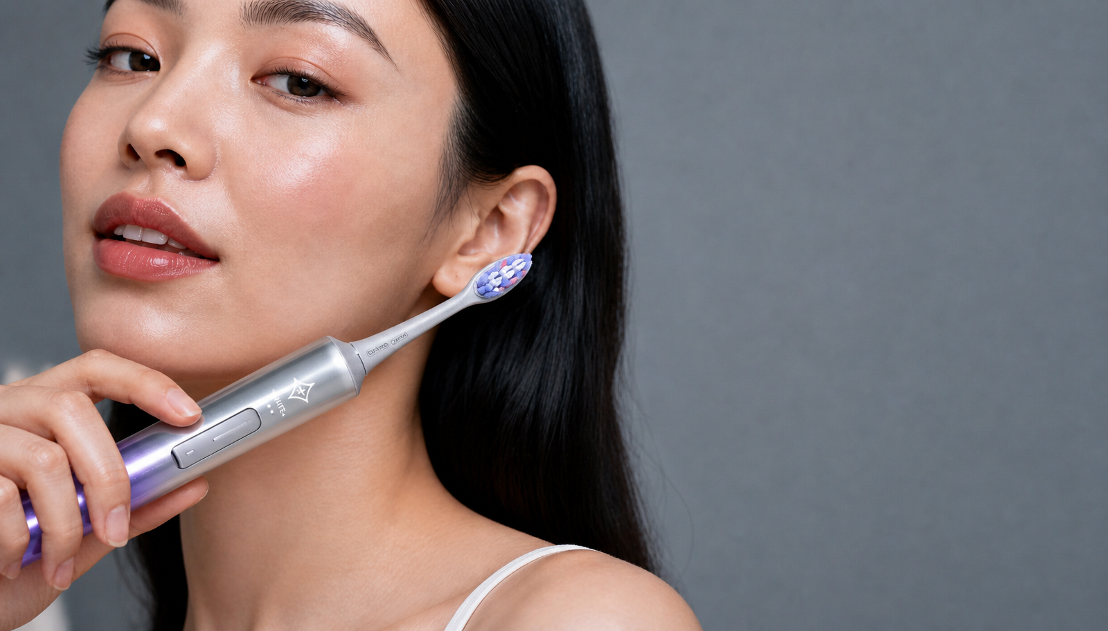 Woman holding a silver electric toothbrush as part of an evening routine